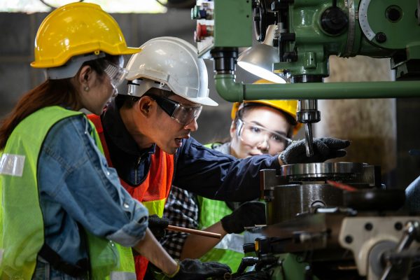 Asian foreman training female trainee worker with the machine