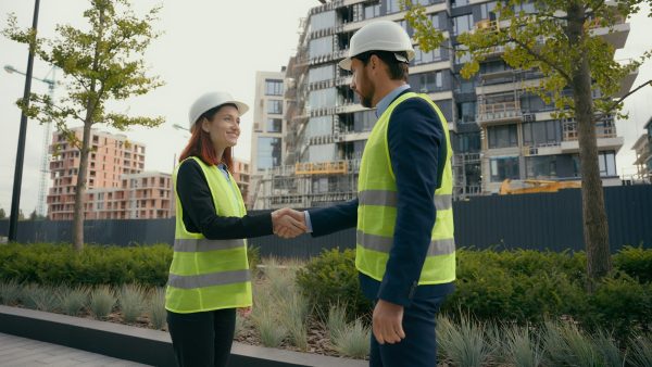 Two people colleagues in safety uniform helmets hardhat engineers managers man and woman female